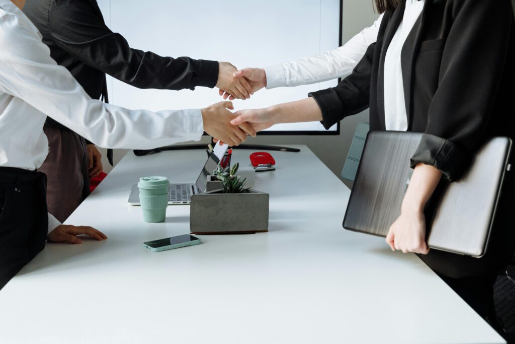 Professionals sealing a deal with a handshake across a conference table during a business meeting.
